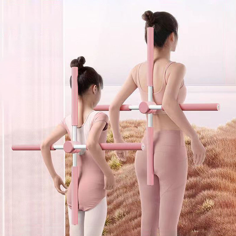 Two girls in pink ballet outfits use SpineCrack Stick posture correction devices on their backs while standing in a field with tall grass, facing away from the camera.